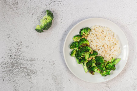 Stir fried broccoli garlic and brown rice has spoon isolated on white slate background close up, top view, healthy vegan food concept.の写真素材