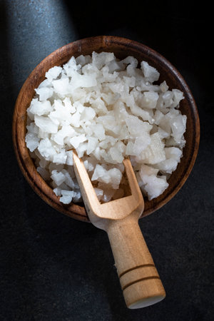 Sea salt crystals in bowl isolated on black stone background close up, top view, copy space, food and drink concept.の写真素材