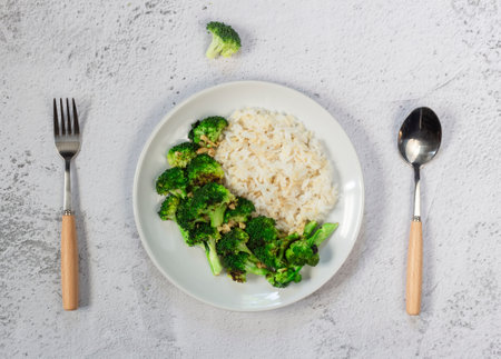 Stir fried broccoli garlic and brown rice has spoon isolated on white slate background close up, top view, healthy vegan food concept.の写真素材