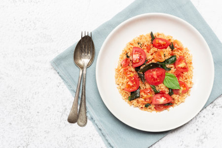 Tomato fried rice has basil in bowl on white slate background, top view, healthy food concept.の写真素材