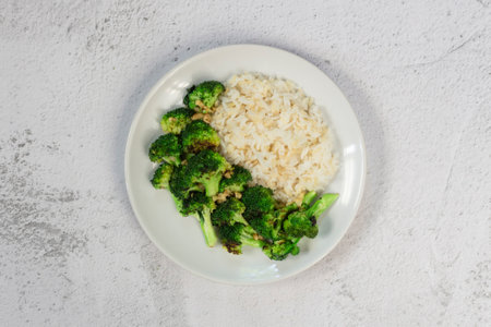 Stir fried broccoli garlic and brown rice has spoon isolated on white slate background close up, top view, healthy vegan food concept.の写真素材