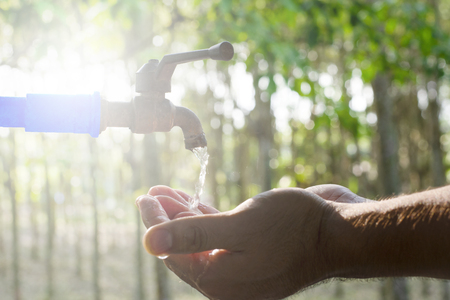 Hand washing on blur green nature background, Water energy conservative concept, Clean hand by water from tap valve, Water supply from faucet, Close up washing hand with copy space, Economical usingの写真素材