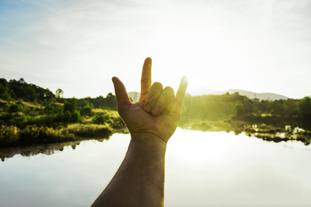 Use hand to touch the sun light in the morning, Love sign, Yellow light with cold air, Flare light from sunrise, holding sun rays, Symbols of hope, pray for godの写真素材
