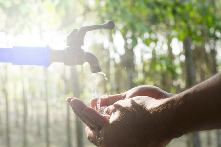 Hand washing on blur green nature background, Water energy conservative concept, Clean hand by water from tap valve, Water supply from faucet, Close up washing hand with copy space, Economical usingの写真素材