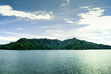 Beautiful landscape view of green mountain beside river on bright sky clouds, Water storage dam,...