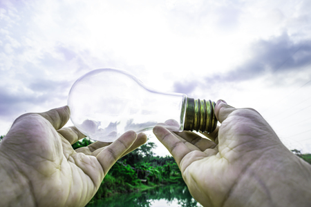 Hand holding light bulb with sunset sky, Use hand hold incandescent lamp for electricity for life...