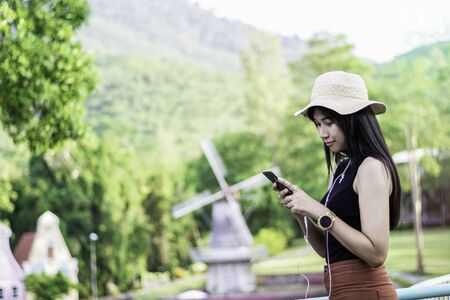 Portrait of asian women sit on the bench relaxing with green nature backgound, Girl listen musics in the morning, Rest on vacation with nature forest, Smilling and chilling girl, Lifestyle conceptの写真素材