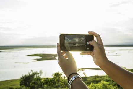Use mobile phone taking the picture of sunset sky