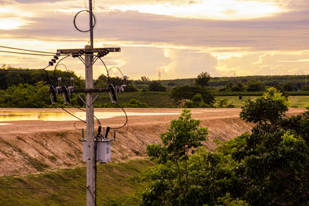 Top view of electricity pylon with green tree on sunset sky, Transmission line of electricity to rural with green natureの写真素材