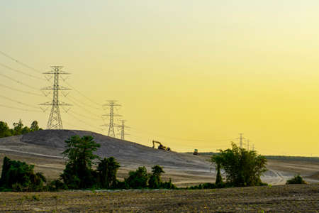 Electricity pole with silhouette sunset sky, Electricity pylon with shadow of tree in dawn time, Electricity power transmission line on sunset with copy space, Electricity pylon on orange skyの写真素材