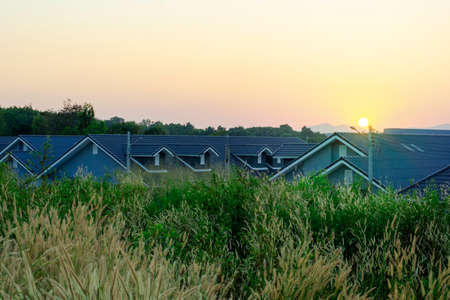 Flare light of sunset over the house roof, Beautiful dramatic sunset on the top of mountainsの写真素材