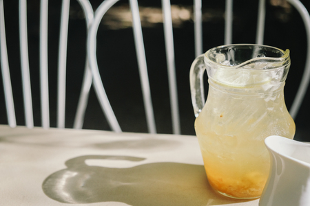 Orange italian soda in the jar of ice on white wooden table in the gardenの写真素材