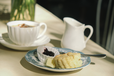 British afternoon tea break ,scones with blue berry fruit jam and clotted cream close-up on the table in the garden.の写真素材
