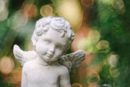 Cupid sculpture in garden the background is blurred bokeh from tree, background for Valentine's day. color toned.の写真素材
