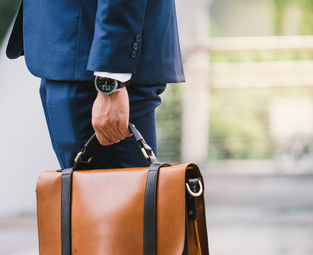 Closeup Of A Businessman wear the watch and Holding leather Briefcase Going To Work with the sunshineの写真素材