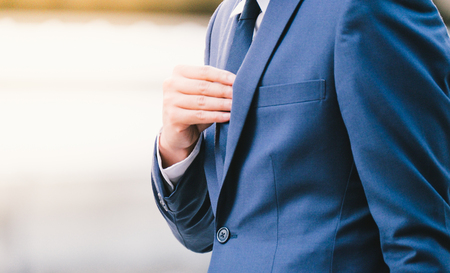 asian business man in suit holding his necktie on a cityscape backgroundの写真素材