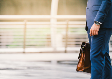 Closeup Of A Businessman wear the watch and Holding leather Briefcase Going To Work with the sunshineの写真素材