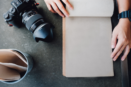 Working table with notebook paper, camera, Vintage Paper , Wooden desk background with copy space on top.の写真素材