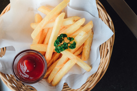 Tasty french fries with ketchup  in wooden plate, on black table backgroundの写真素材