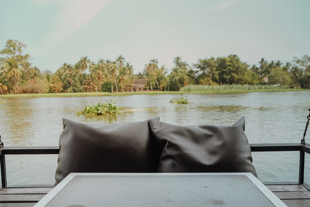 Relax corner on restaurant near the river with comfortable chairs on the ground. Relax slow life concept. Vintage toneの写真素材