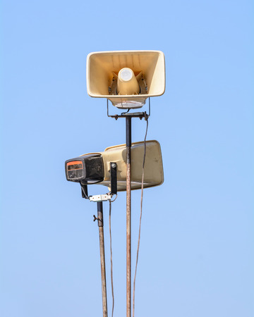 Old loudspeakers on steel pole on blue skyの写真素材