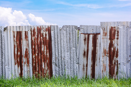 Rusty galvanized corrugated fence with the blue sky and cloudyの写真素材