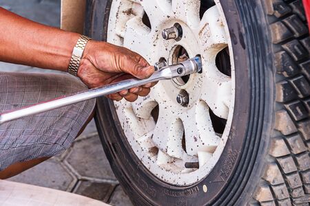 Mechanic technician worker replacing wheel vehicle of automobile at repair service station.の写真素材