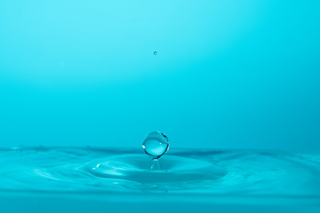 Water drop falling down. Abstract blue background.の写真素材