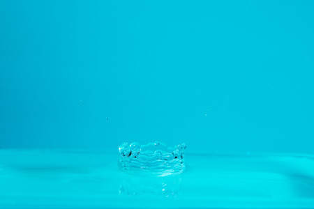Water drop falling down. Abstract blue background.の写真素材