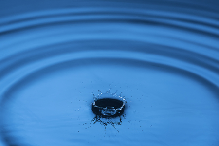 Water drop falling down. Abstract blue background.の写真素材