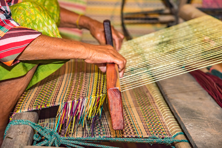 Closeup old woman hands weaving mats from dry reed.の写真素材