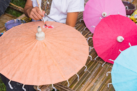 Yong girl painting on Handmade umbrella of the village Bo Sang, Chiang mai, Thailand.の写真素材