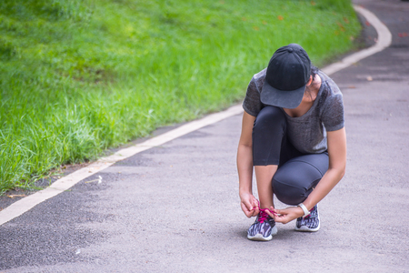 Runner woman getting ready for run tying laces of running shoes.の写真素材