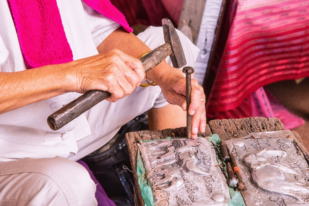 Hands of the craftsman hitting silverware a bas-relief with hammer.の写真素材