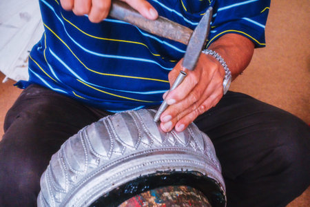 Hands of the craftsman hitting silverware a bas-relief with hammer.の写真素材