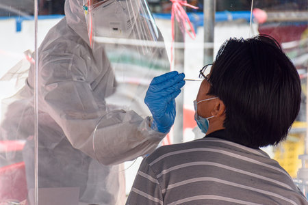 CHIANG MAI, THAILAND - JULY 24, 2021: Health workers in a protective suit conduct a COVID-19 test...
