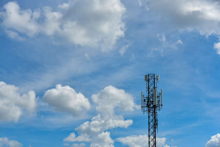 Telecommunication towers with clouds on blue sky background. Tower signal in blue sky white clouds backgroundの写真素材