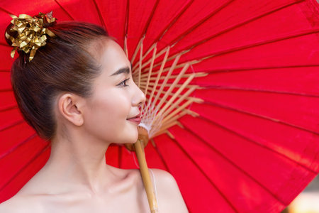 Thai woman dressed in traditional Northern Thailand culture costume holding a paper umbrella. Identity culture of Thailandの写真素材