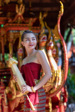 Thai woman dressed in traditional Northern Thailand culture costume holding a paper umbrella. Identity culture of Thailandの写真素材