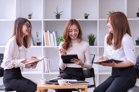 Three young Asian businesswomen discussing a new Idea Presentation business project In Modern...
