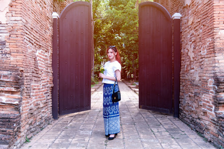 Young Asian women dressed in traditional costumes visit an old temple in Thailand. Tourist visit ancient sites concept.の写真素材