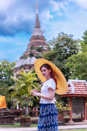 Young Asian women dressed in traditional costumes visit an old temple in Thailand. Tourist visit ancient sites concept.の写真素材
