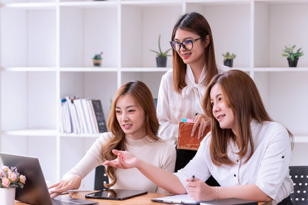 Three young Asian businesswomen discussing a new Idea Presentation business project In Modern Office. Asian business casual concept.の写真素材