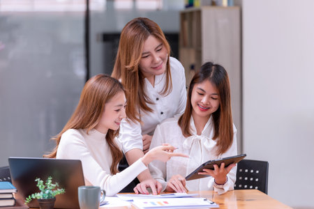Three young Asian businesswomen discussing a new Idea Presentation business project In Modern Office. Asian business casual concept.の写真素材