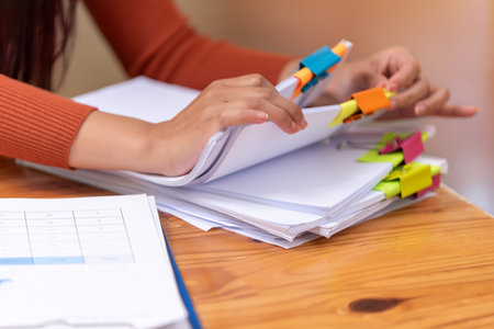 Businesswoman hands working for searching in Stacks of paper documents on wooden desks at the...