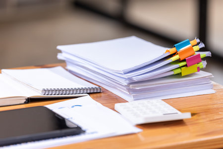 Paper documents are stacked on wooden desks at the workplace. Business Concept.