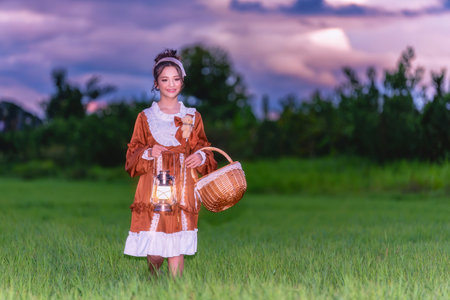 Young girl holding a lantern in the green meadow. Girl enjoys and cheerfully in the fieldの写真素材