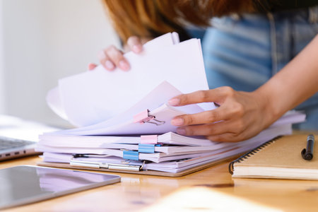 Hand of searching in Stacks of paper documents on wooden desks at the workplace. Business's casual...