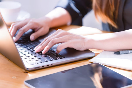 Hand of a businesswoman standing working with a laptop in the office. Business's casual and...