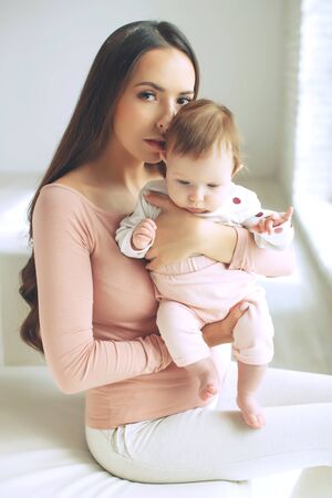 Beautiful woman with a baby is resting in a cozy house.の写真素材